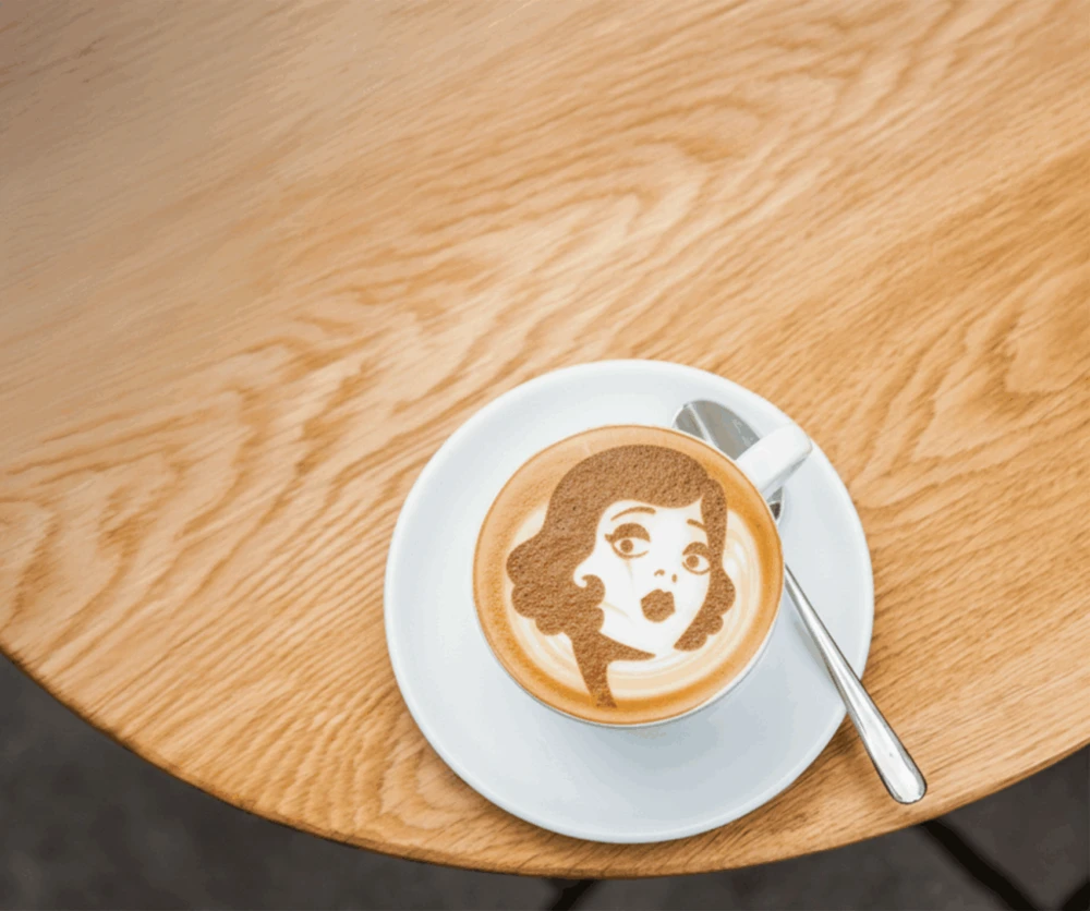 Káva s charakteristickým latte art Mondieu na drevenom stole v Eurovei